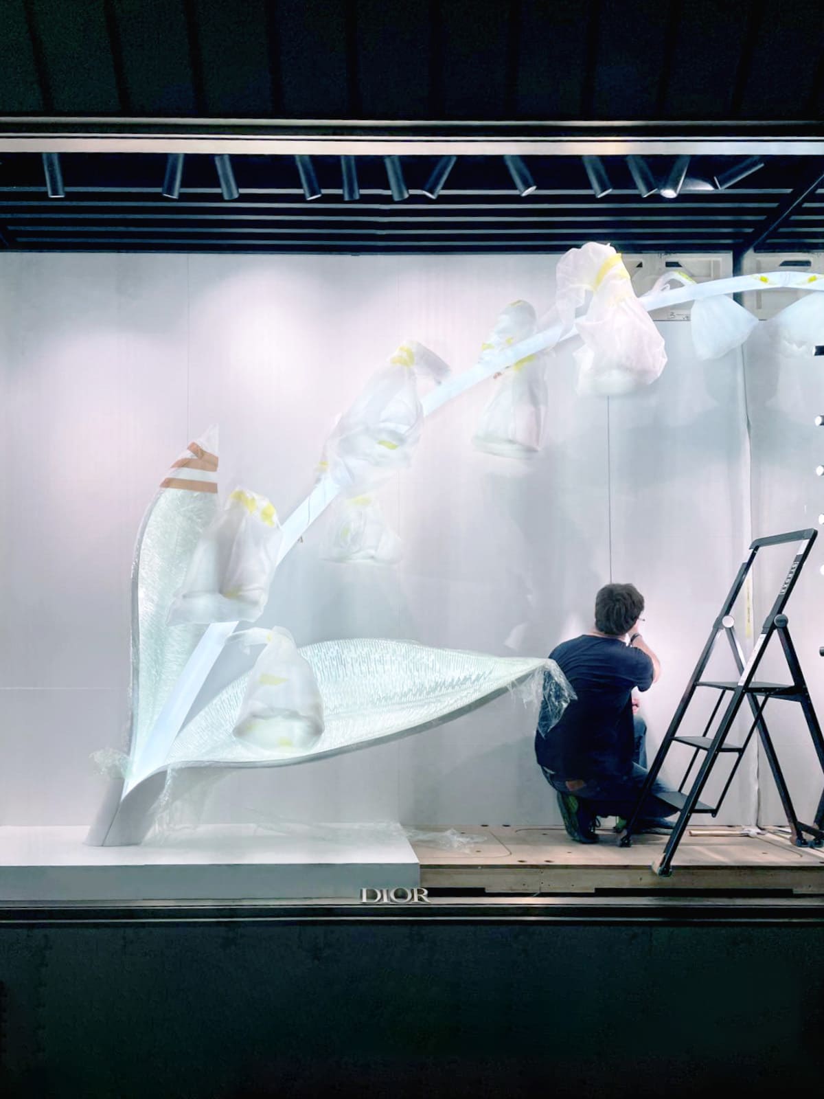 Montage vitrine Dior menuisier ajustement porte cachée fond scénographie Paris